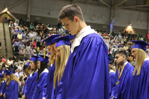 Benton Barber and the rest of the graduates bow their heads for the invocation. 