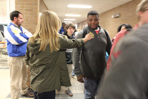 Callie Philips gives sticky notes with a positive message to Jasper Gardner and other students as they head to second block.