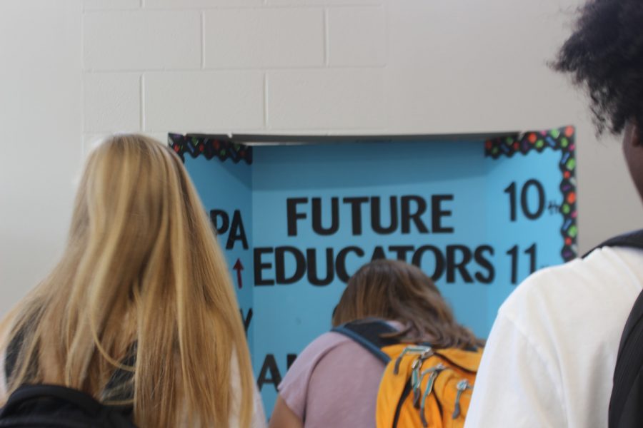 Students get in line to sign Future Educators Club Board.