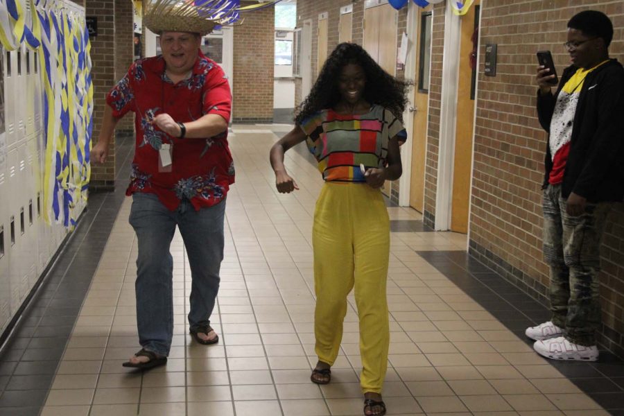 Mr. Hinds and Jaiza Ford sliding down the hallway on Hawaiian Day