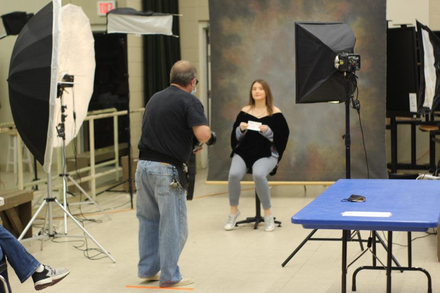 Marty Pettit takes a picture of senior Abby Grace. you can see her mask on the table. She is following covid guidelines.