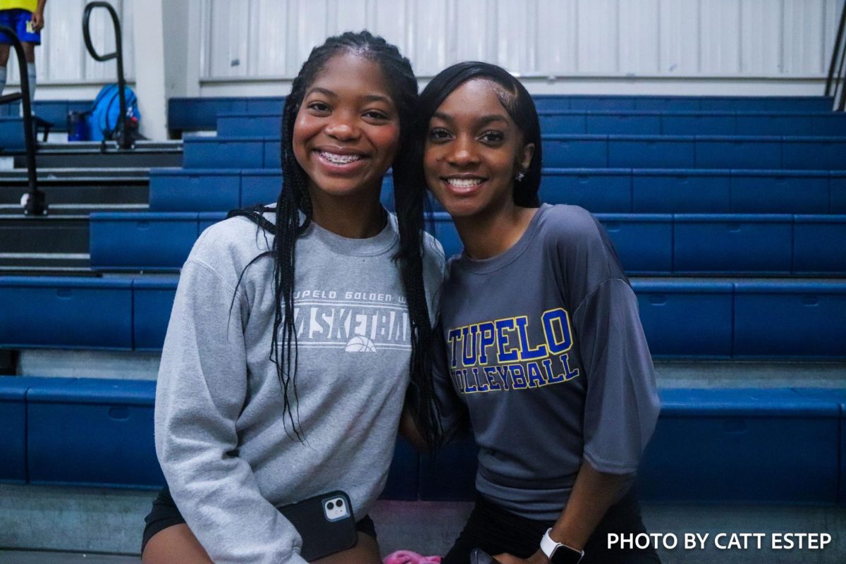 Kylon White and Kamryn Harris smile together on the sidelines. 