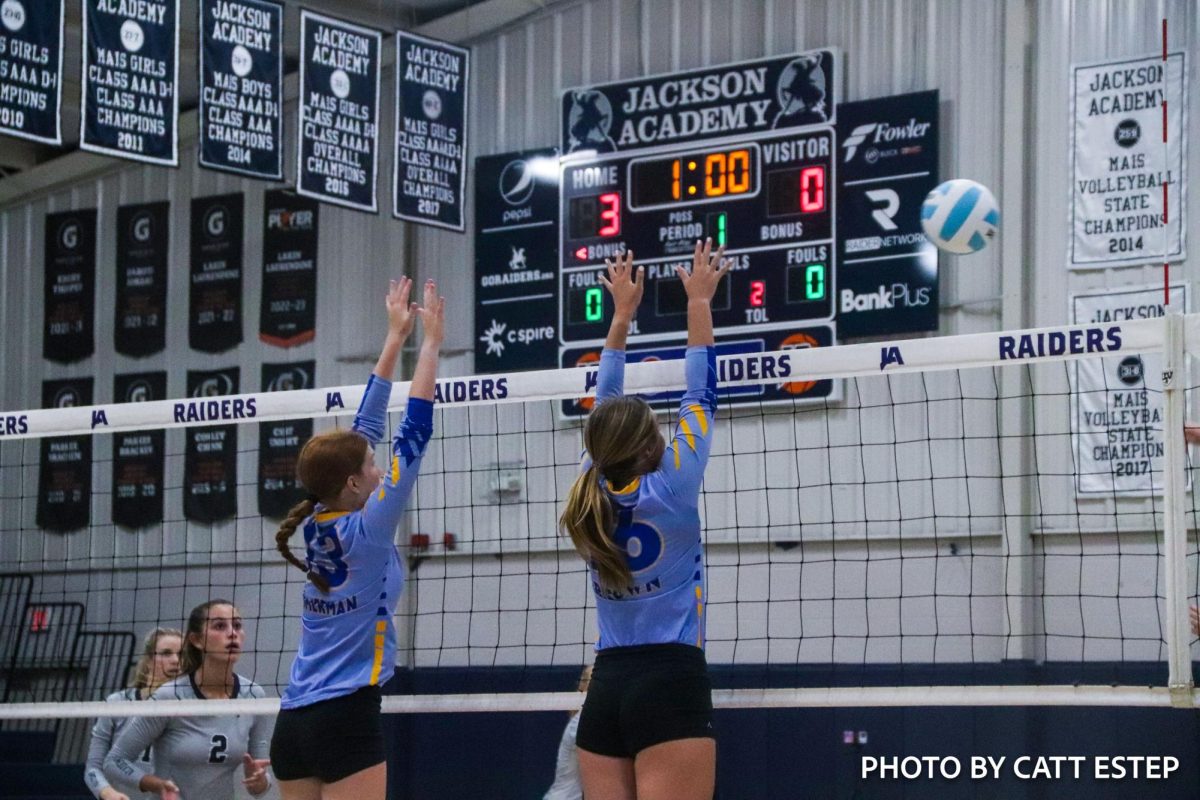 Loren Zimmerman and Sarah Foster Brown jump up to block the ball from the opposing team. 