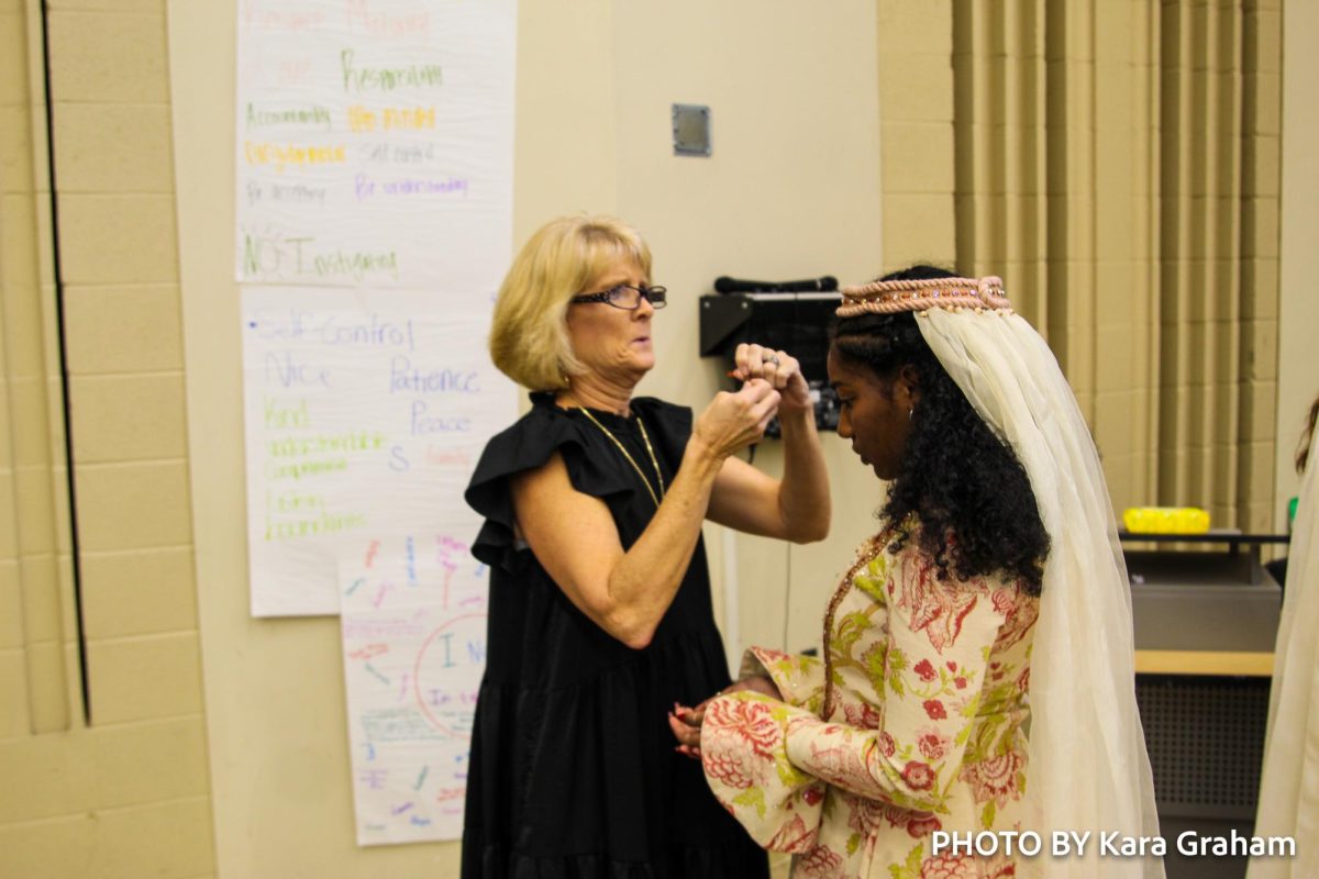 Madrigals director, Suzy Williams, fixes Alissa Pattersons (10) veil before the performance 