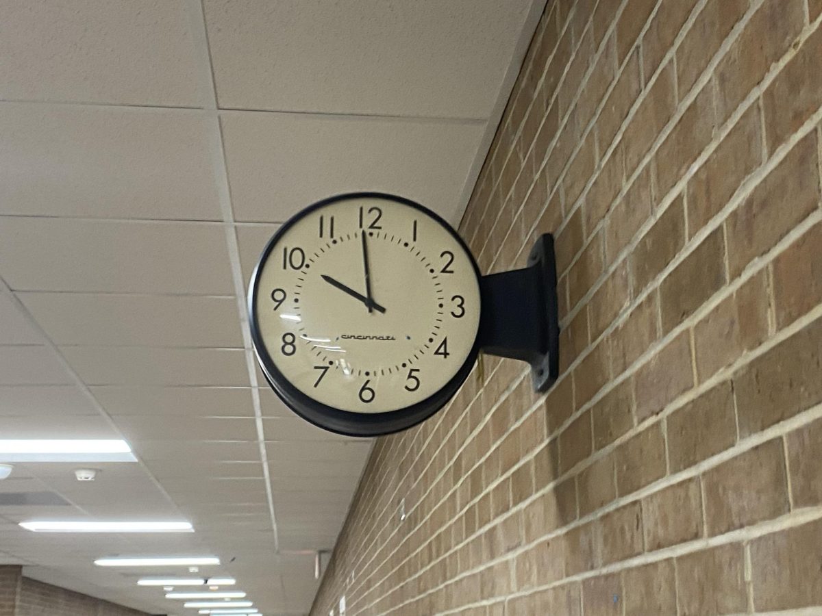 A photo of a clock in a school hallway.