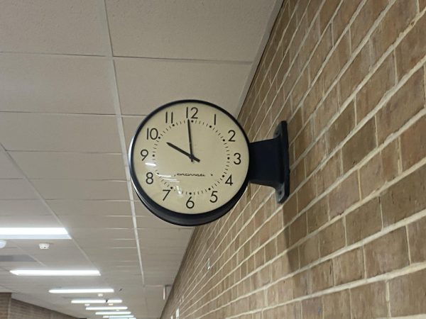 A photo of a clock in a school hallway.