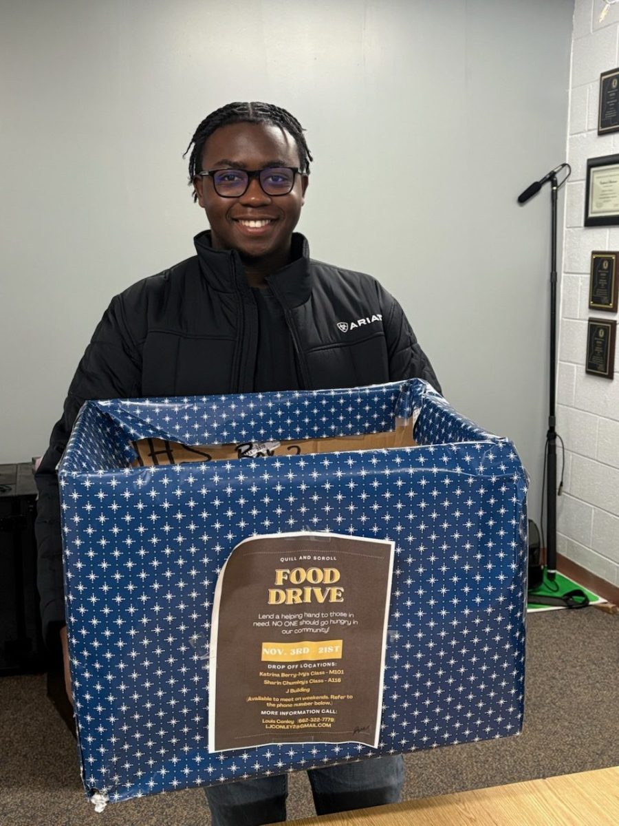 LJ Conley shows off the collection boxes for the Quill and Scroll food drive. 